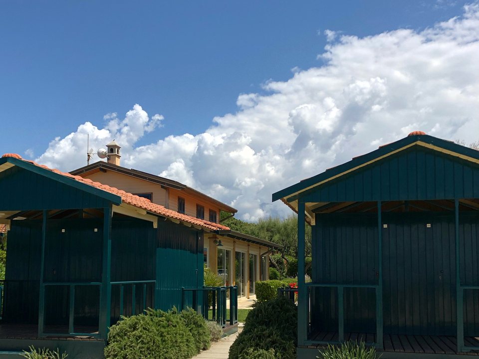 Due cabine versiliesi in legno verde davanti alla casa del bagno